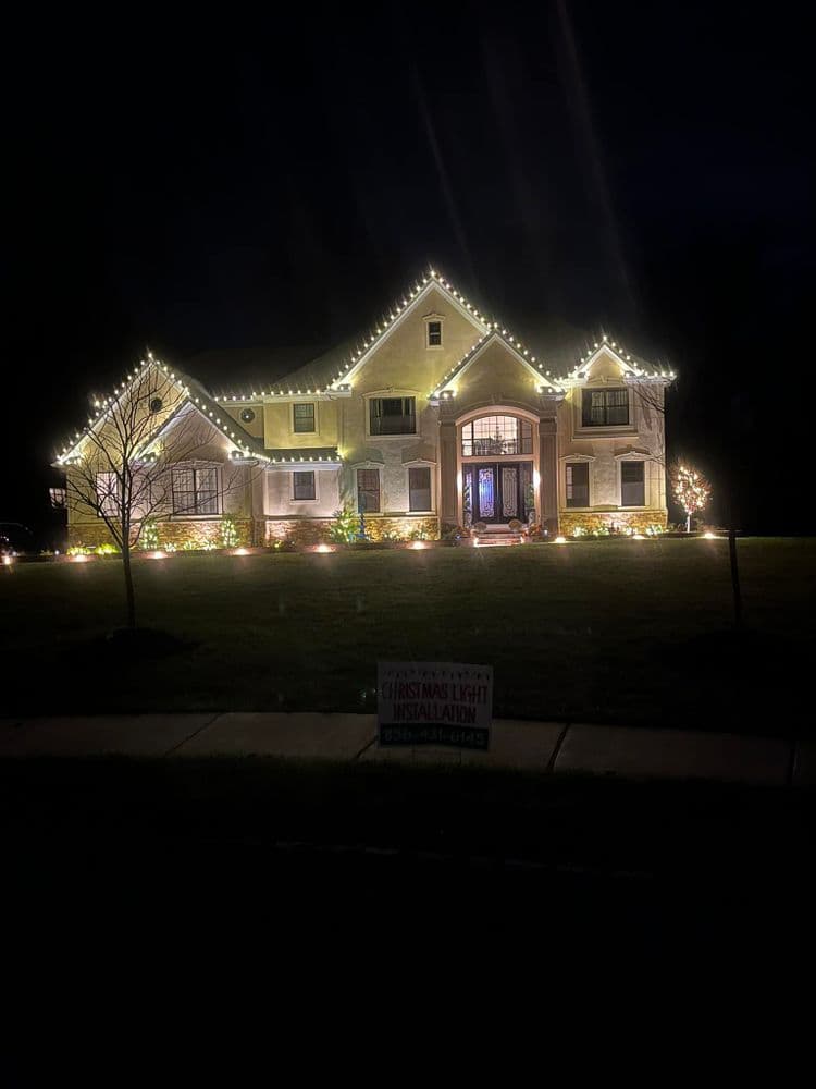 Elegant two-story house adorned with festive Christmas lights at night.