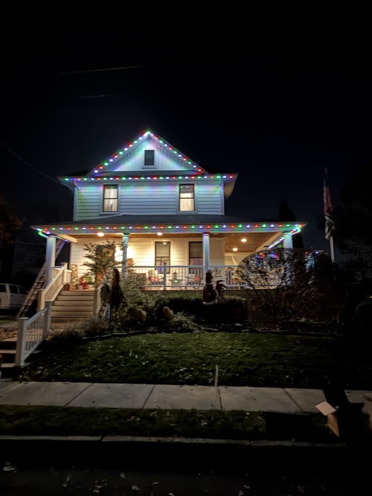 Decorated house with colorful Christmas lights at night, showcasing festive holiday spirit.