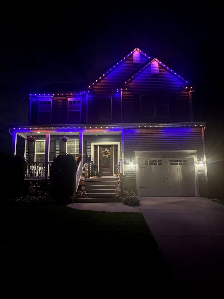 House decorated with purple and blue lights for nighttime display, featuring a welcoming front porch.