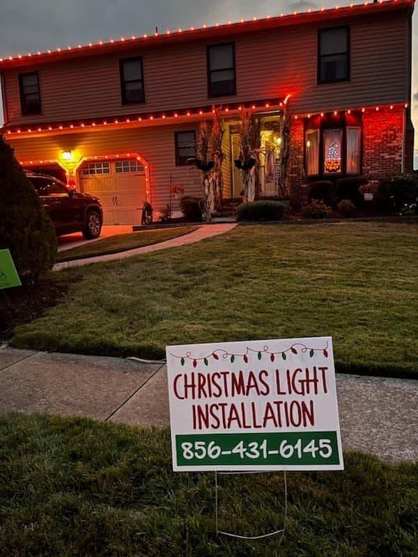 Home decorated with Christmas lights, featuring a sign for installation services.