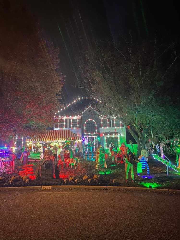 Decorated house with colorful Christmas lights and themed Halloween decorations at night.