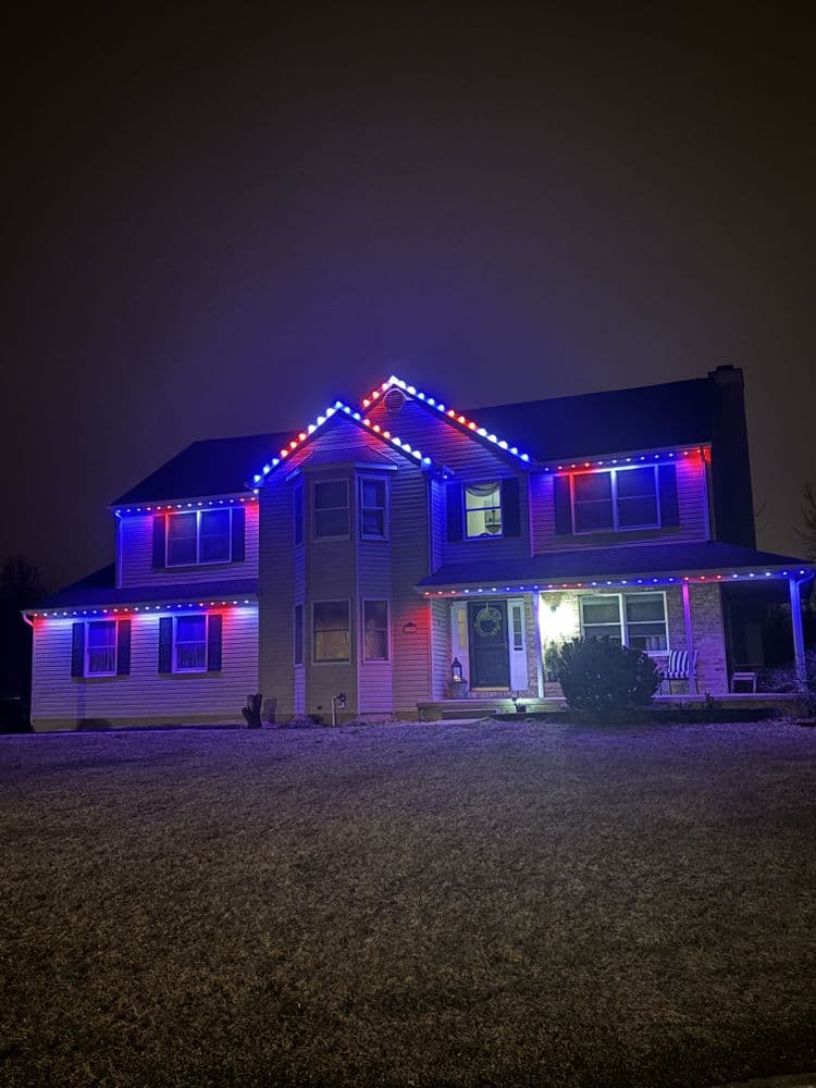 House decorated with red and blue lights for the holiday season at night.