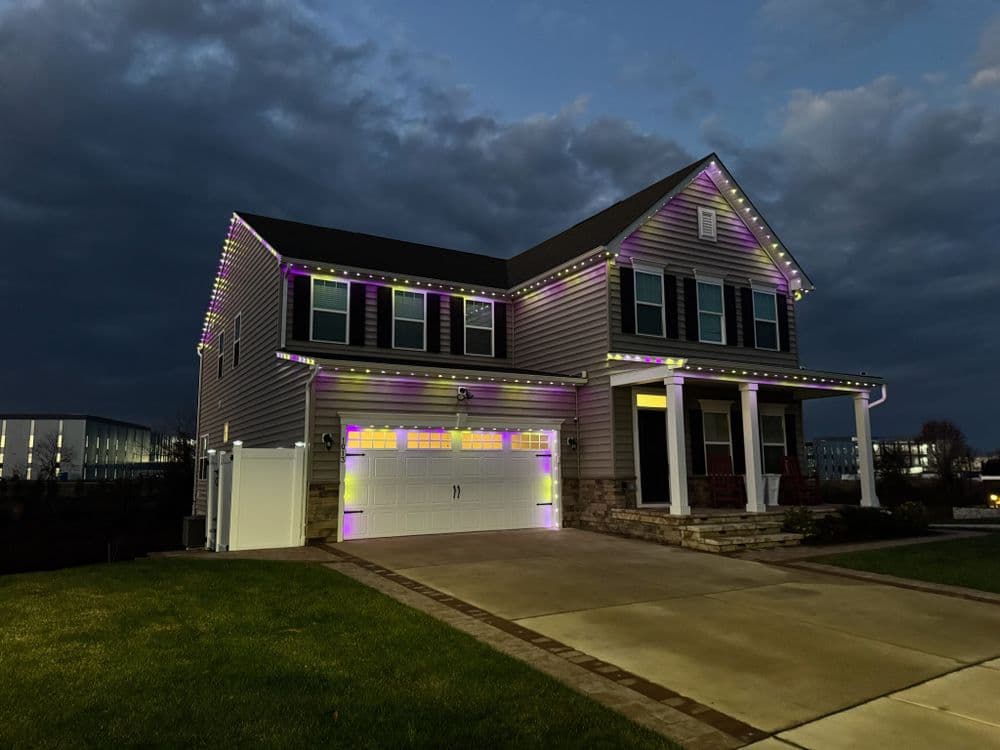 Modern house decorated with colorful lights for festive season, set against a twilight sky.