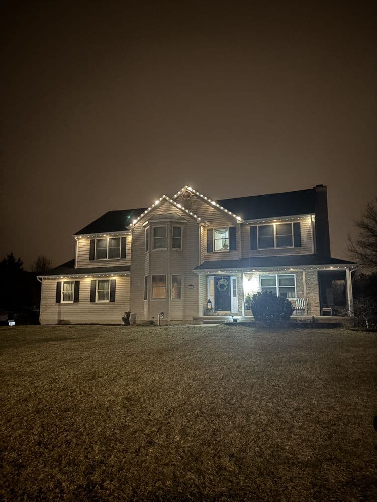 Two-story house decorated with holiday lights at night, showcasing its charming architecture.