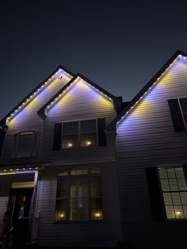Home exterior decorated with blue and yellow lights at night, creating a festive atmosphere.
