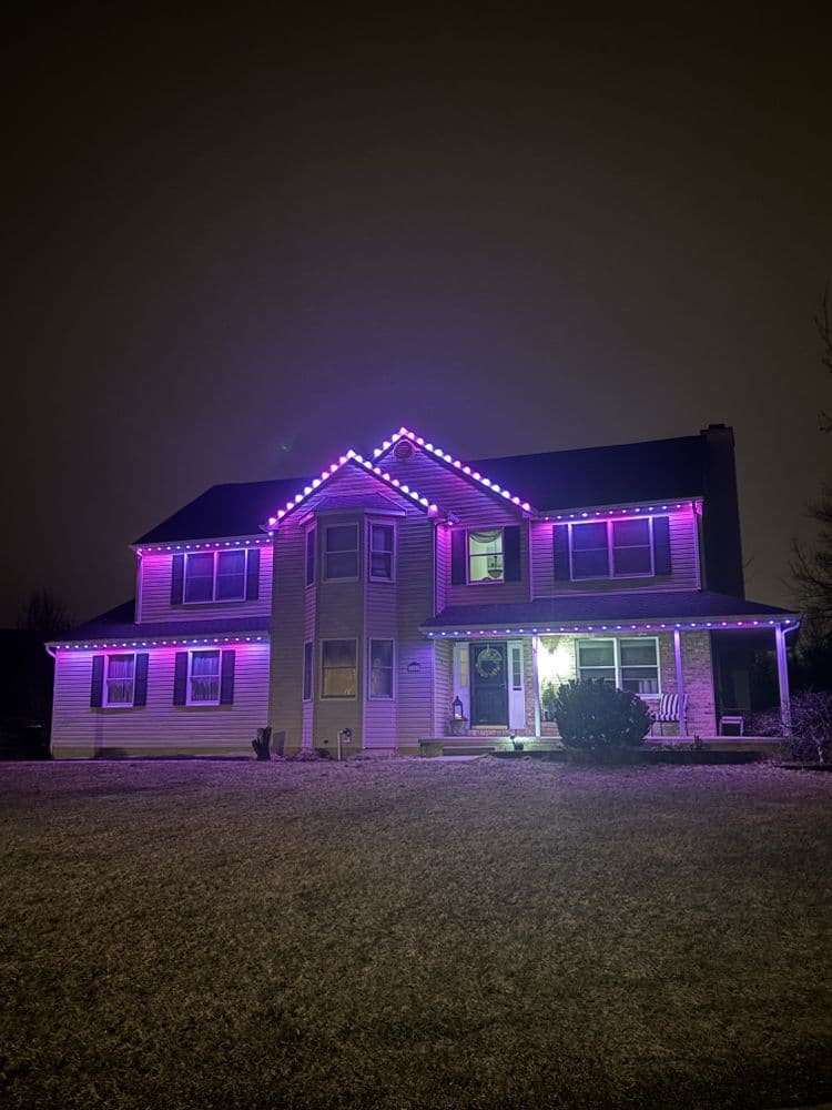 House decorated with vibrant purple lights, showcasing a festive holiday atmosphere.