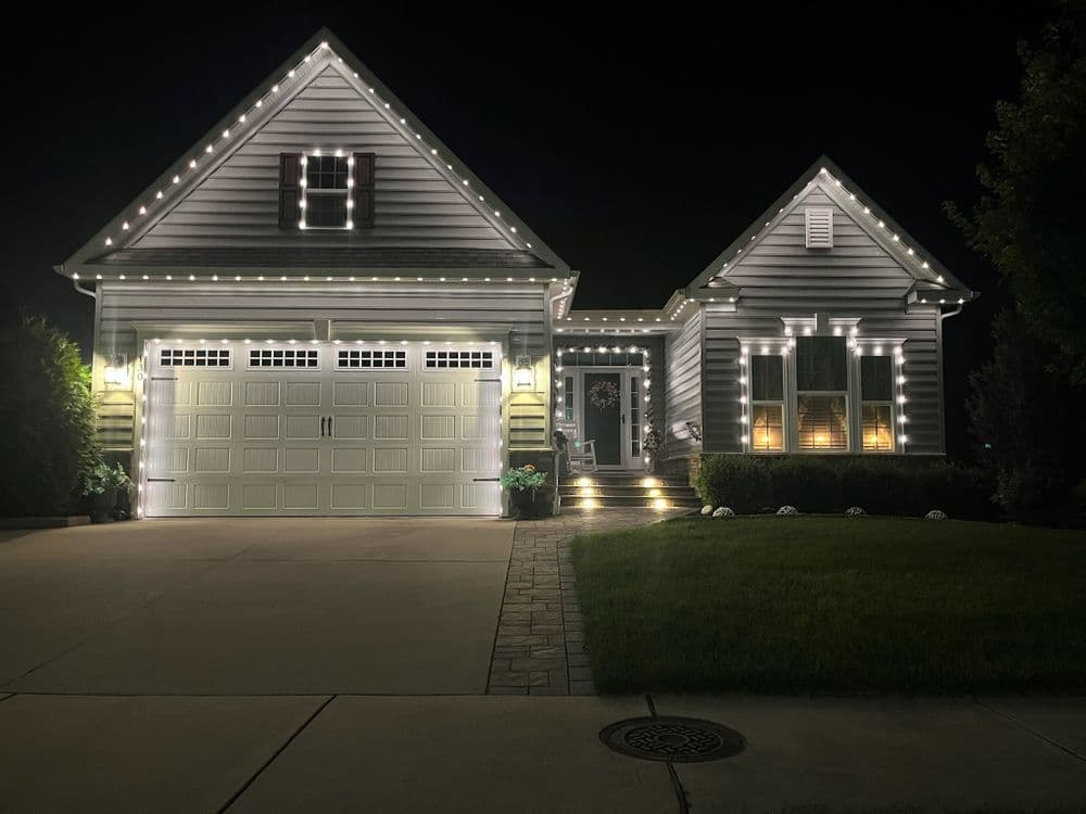 Modern house at night with decorative lights on exterior and well-lit entryway.