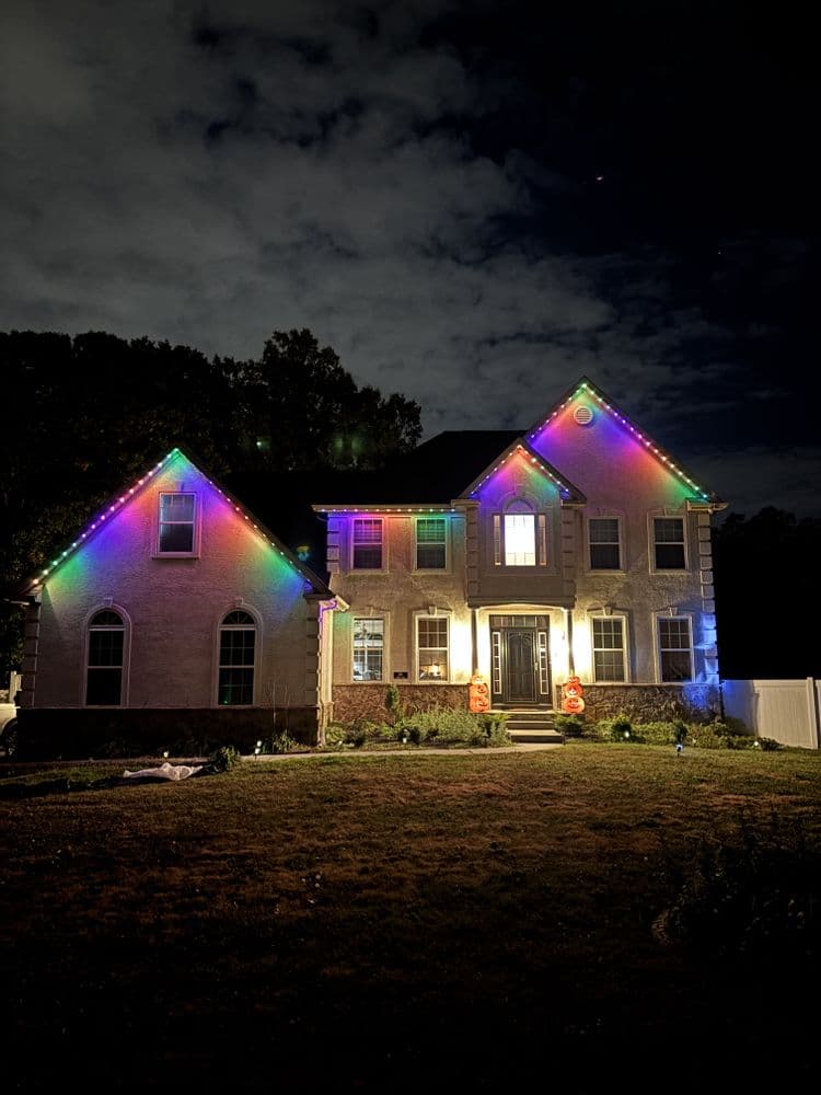 Colorful Christmas lights adorning a suburban home at night, festive holiday decor.