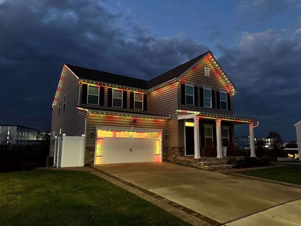 Colorful holiday lights adorning a modern home at dusk with cloudy sky.