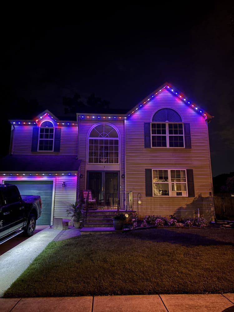 Modern house decorated with purple and blue lights for nighttime festivities.