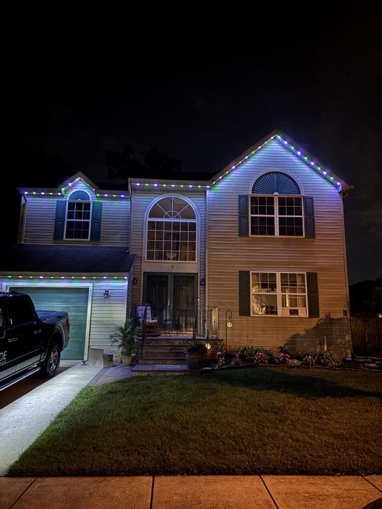 Two-story house decorated with colorful lights at night, showcasing a welcoming entrance.