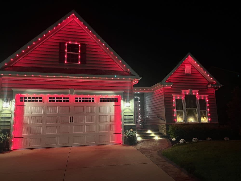House decorated with red holiday lights at night, showcasing festive outdoor design.