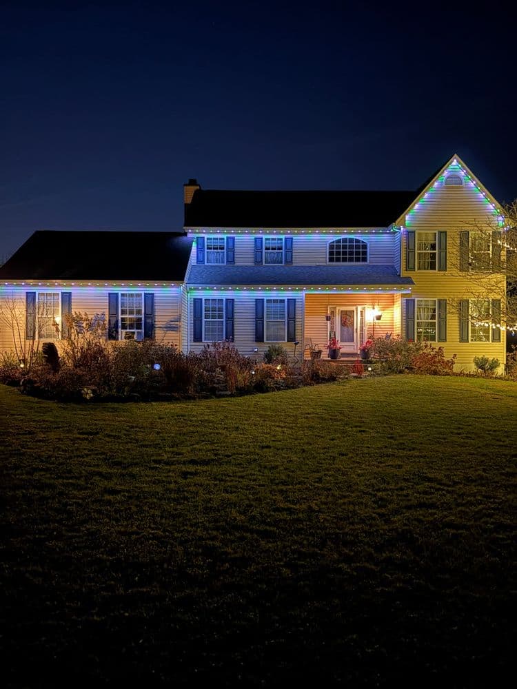 Festively decorated house with colorful lights at night, showcasing holiday spirit and charm.