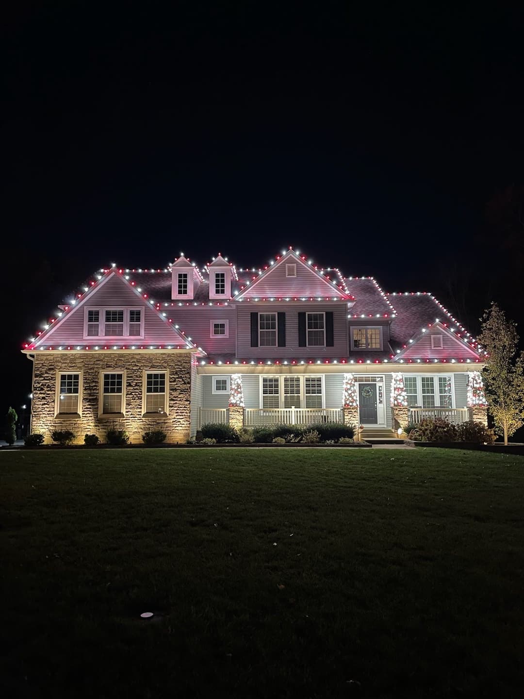 Festively decorated house with pink and white lights glowing at night. Cozy holiday ambiance.