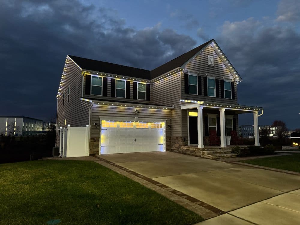 Two-story home decorated with festive lights, evening sky, and well-maintained lawn.
