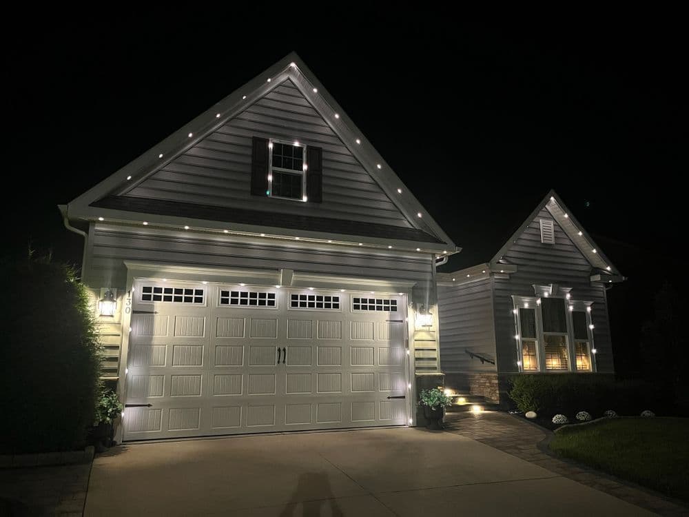 Beautifully lit house at night with decorative lights outlining the roof and garage.
