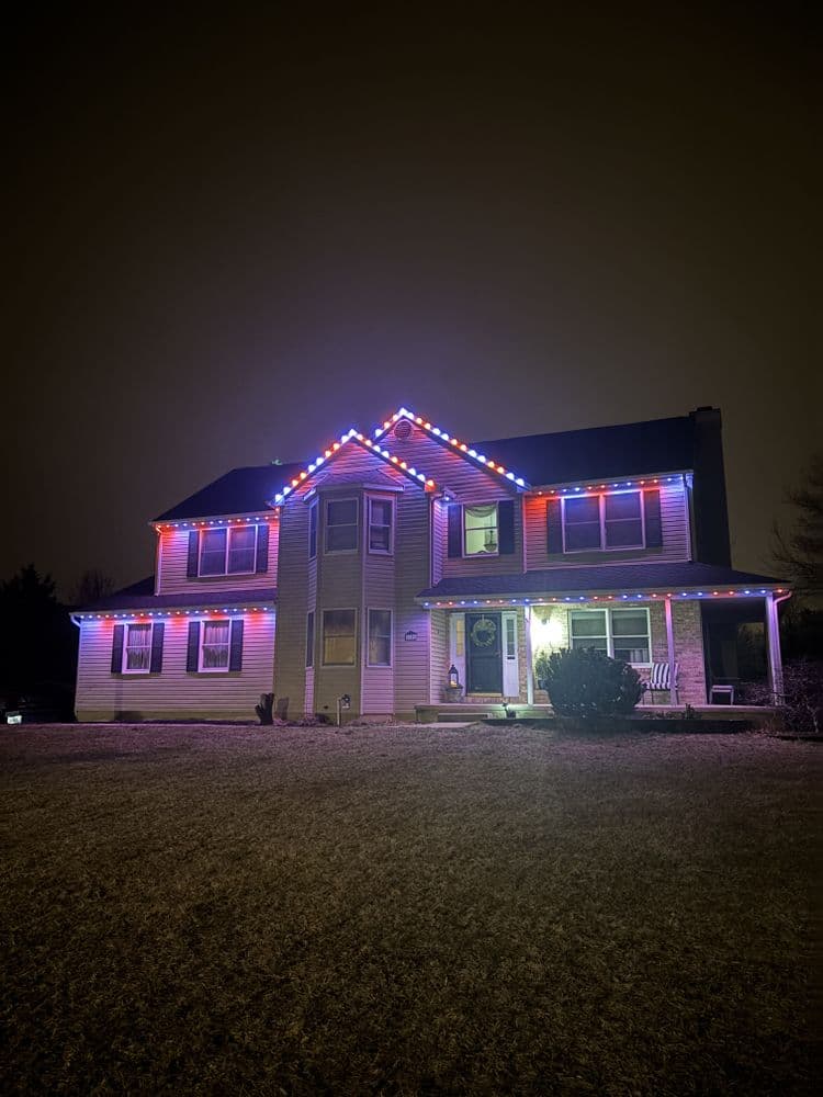 House decorated with colorful Christmas lights in a nighttime setting, highlighting festive cheer.