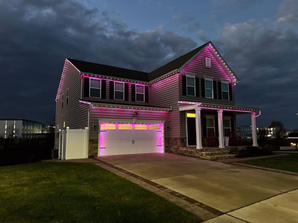 Home decorated with pink outdoor lights at dusk, showcasing modern architecture and landscaping.