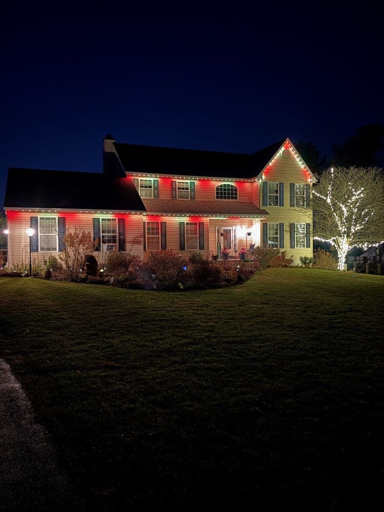 Festively lit home with red and green lights, showcasing holiday charm at night.