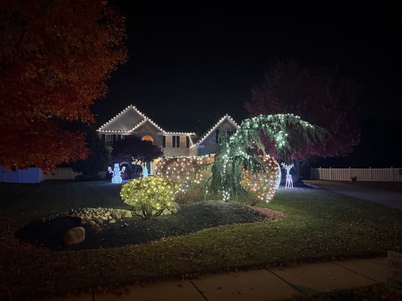 Festively lit house with holiday decorations and glowing trees at night.