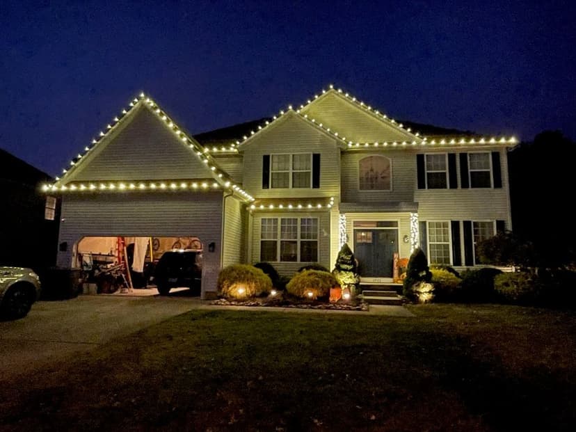 Two-story house decorated with string lights for the holidays at night.