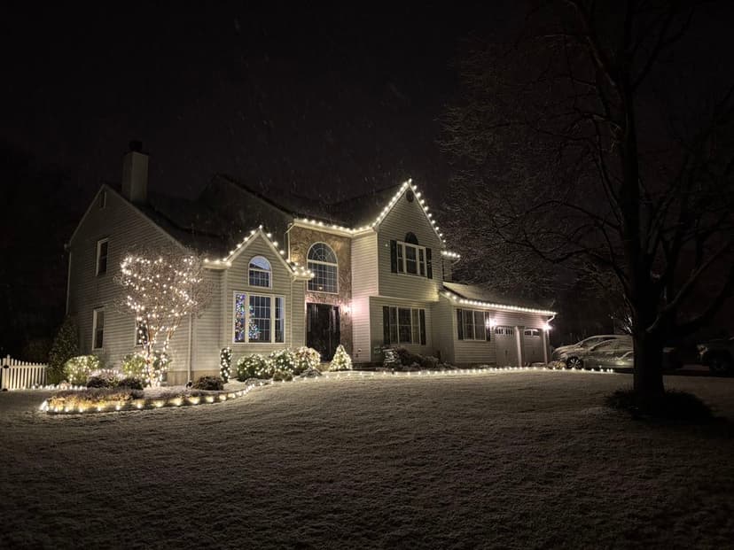 Snowy house decorated with festive lights during winter night. Holiday spirit and cozy ambiance.